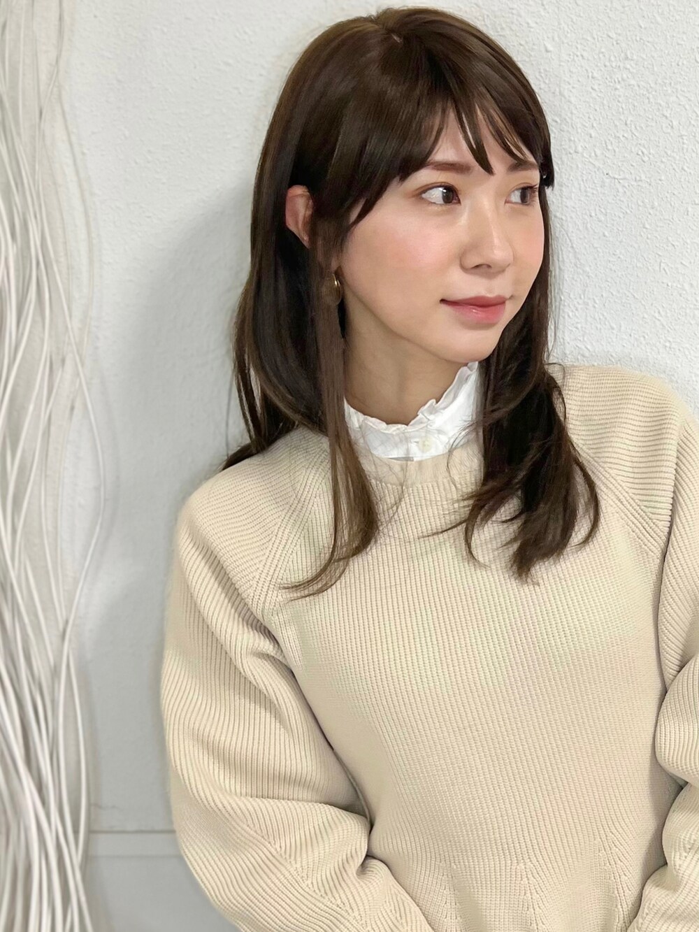 ブラウン系のチェスターコート、ブラウン系のブーツ、ベージュ系のワンピースを着用したレディースの冬コーディネートの2枚目の写真