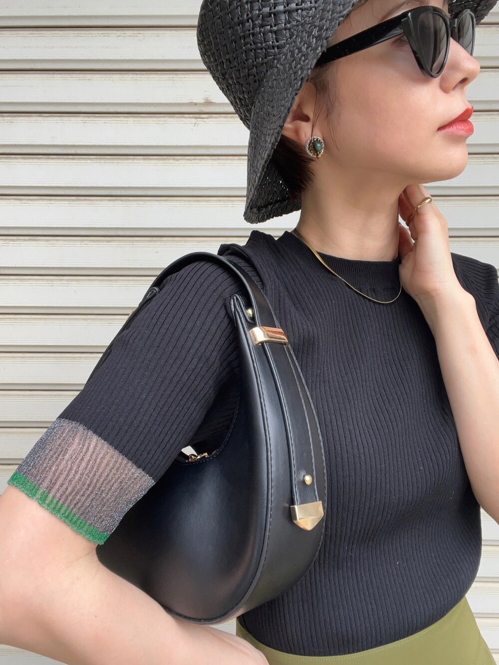 ブラック系のニット/セーター、グリーン系のスカート、ブラック系のサンダルを着用したレディースの夏コーディネートの2枚目の写真