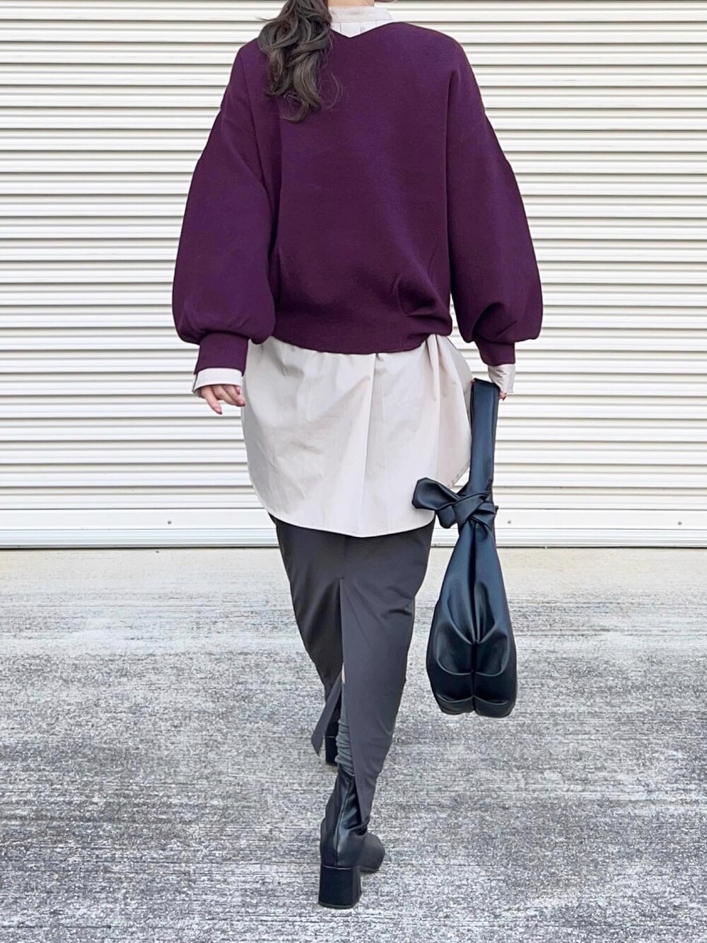 パープル系のニット/セーター、グレー系のスカート、ブラック系のハンドバッグを着用したレディースの秋コーディネートの2枚目の写真