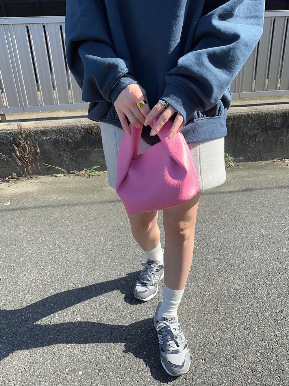 ピンク系のハンドバッグ、グレー系のスニーカー、ブルー系のスウェットを着用したレディースの秋コーディネートの2枚目の写真