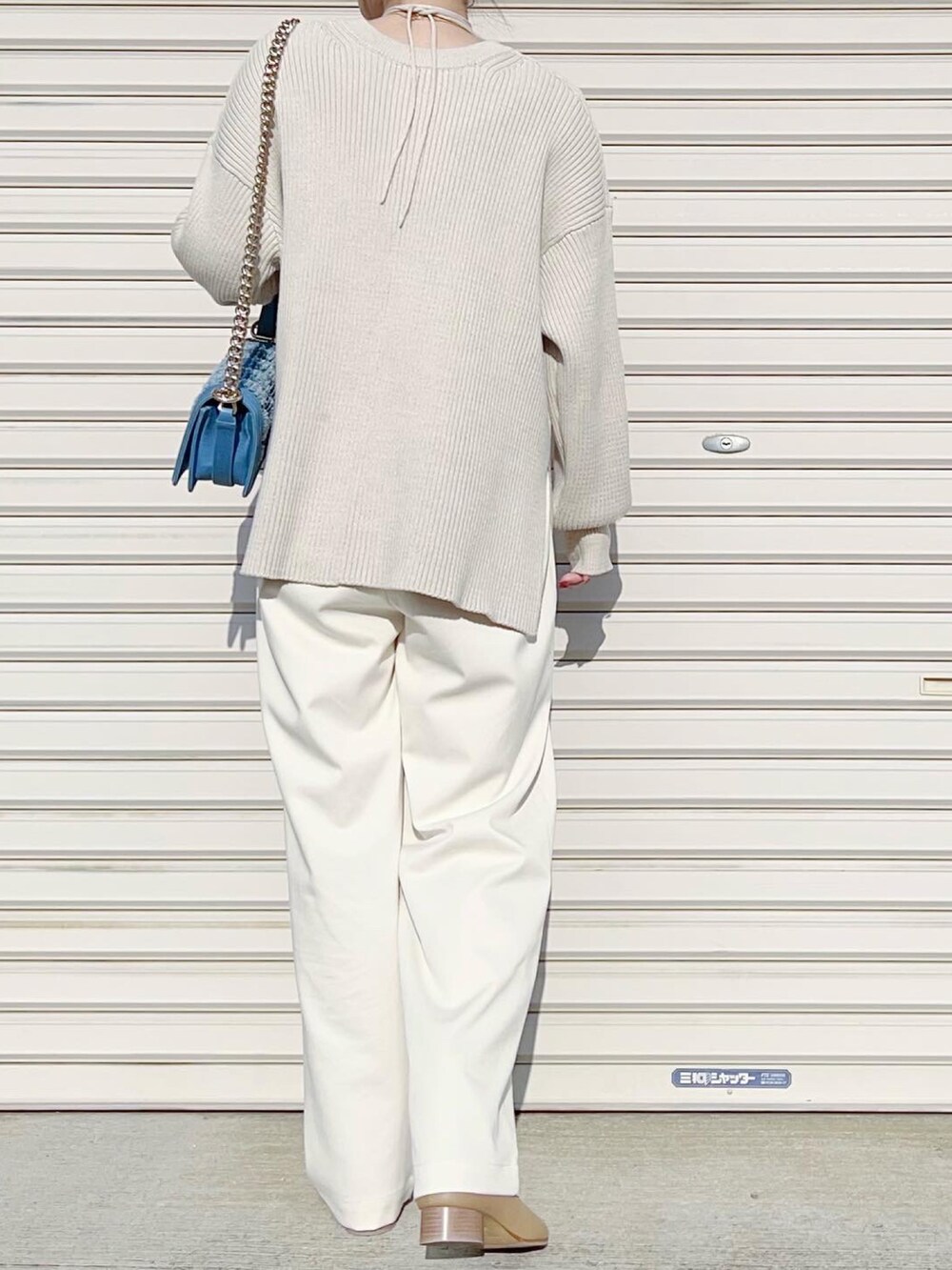 ホワイト系のニット/セーター、ホワイト系のスラックス、ベージュ系のブーツを着用したレディースの冬コーディネートの2枚目の写真