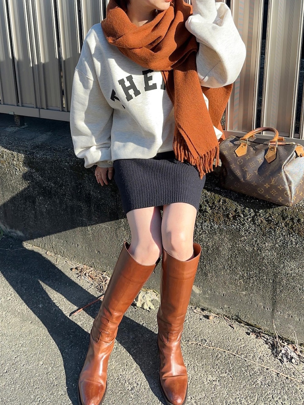 ベージュ系のスウェット、ブルー系のスカート、ブラウン系のブーツを着用したレディースの秋コーディネートの3枚目の写真