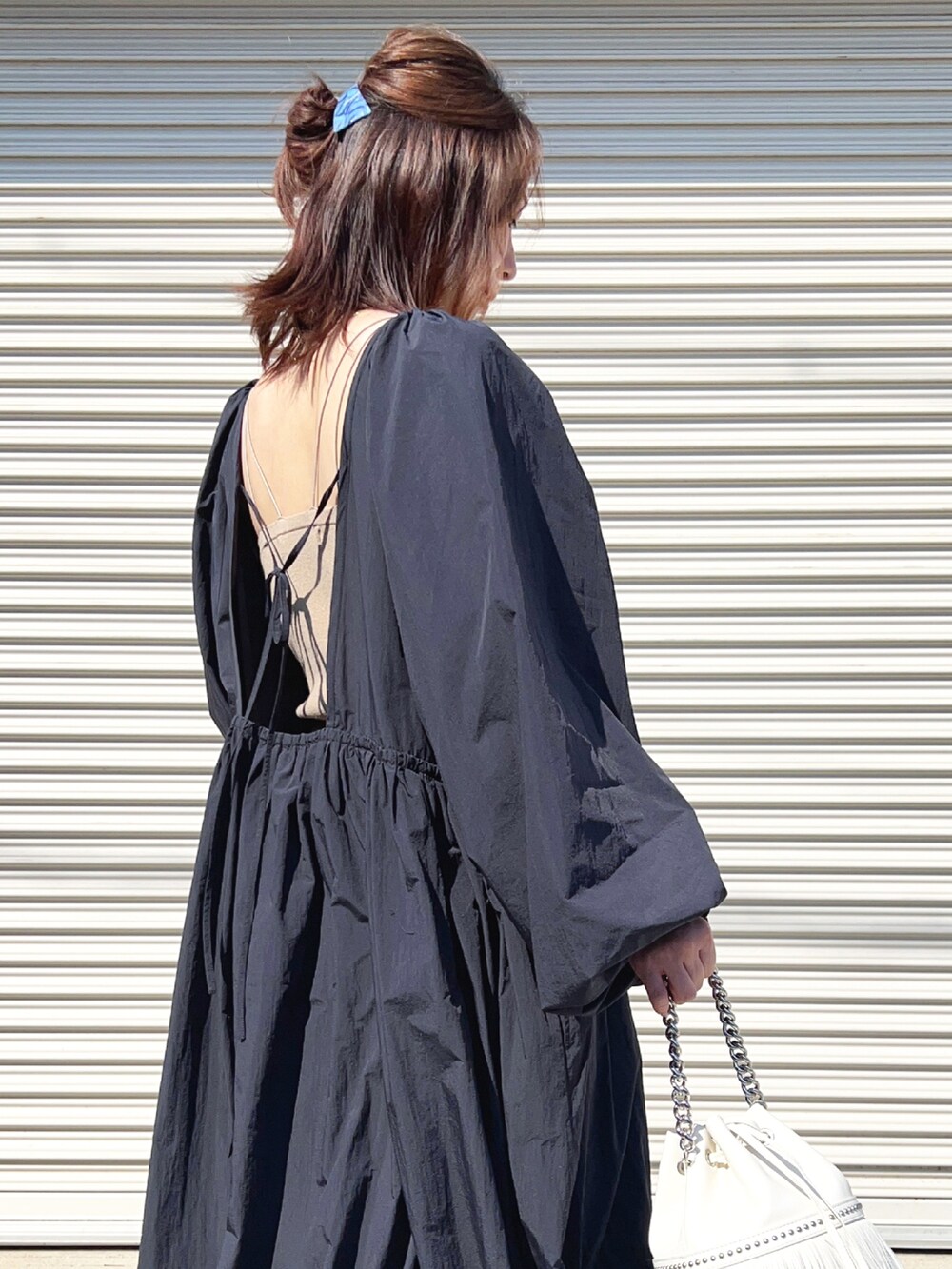 ブルー系のワンピース、ホワイト系のサンダル、ホワイト系のショルダーバッグを着用したレディースの春コーディネートの2枚目の写真