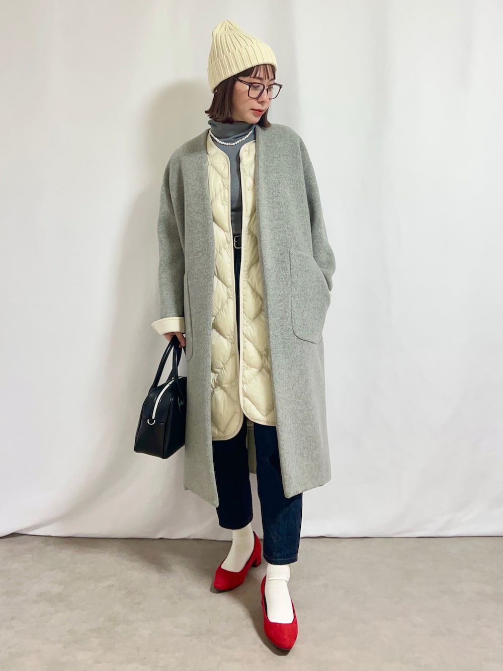 ホワイト系のベスト、グレー系のトップス、ブルー系のデニムパンツを着用したレディースの冬コーディネートの2枚目の写真