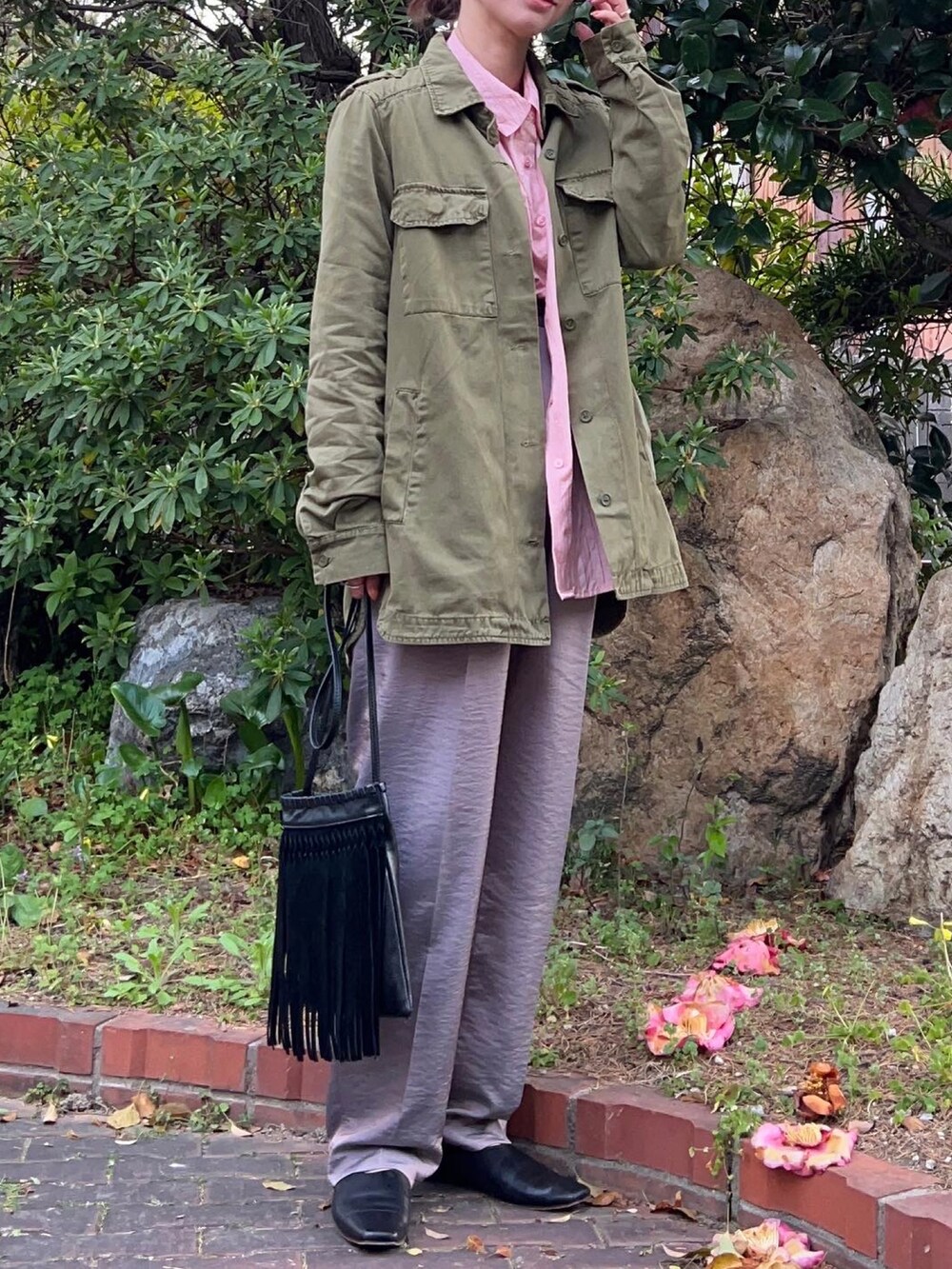 ピンク系のシャツ/ブラウス、ブラック系のショルダーバッグ、パープル系のスラックスを着用したレディースの春コーディネートの2枚目の写真