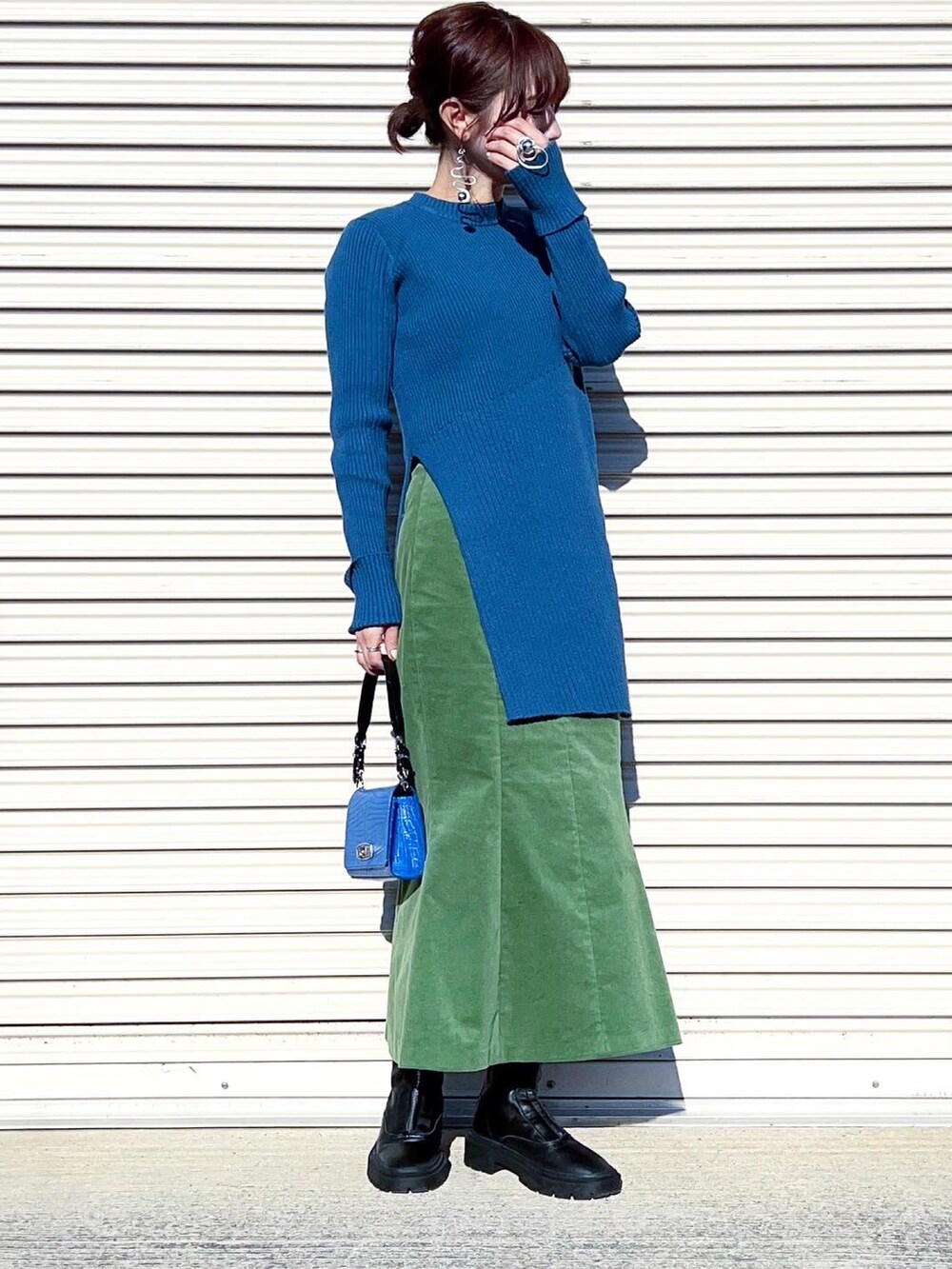 ブルー系のニット/セーター、ブラック系のカーディガン/ボレロ、グリーン系のスカートを着用したレディースの冬コーディネートの2枚目の写真