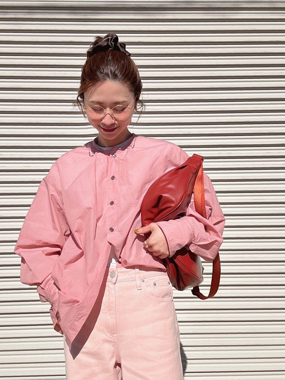 レッド系のショルダーバッグ、ピンク系のシャツ/ブラウス、ピンク系のデニムパンツを着用したレディースの冬コーディネートの2枚目の写真