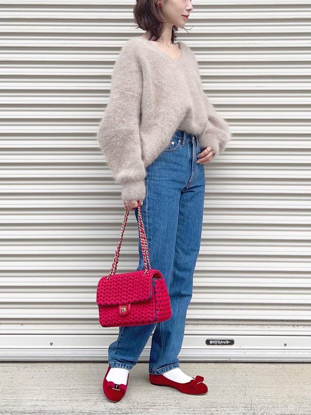 レッド系のバレエシューズ、ホワイト系のニット/セーター、ブルー系のデニムパンツを着用したレディースの冬コーディネートの2枚目の写真