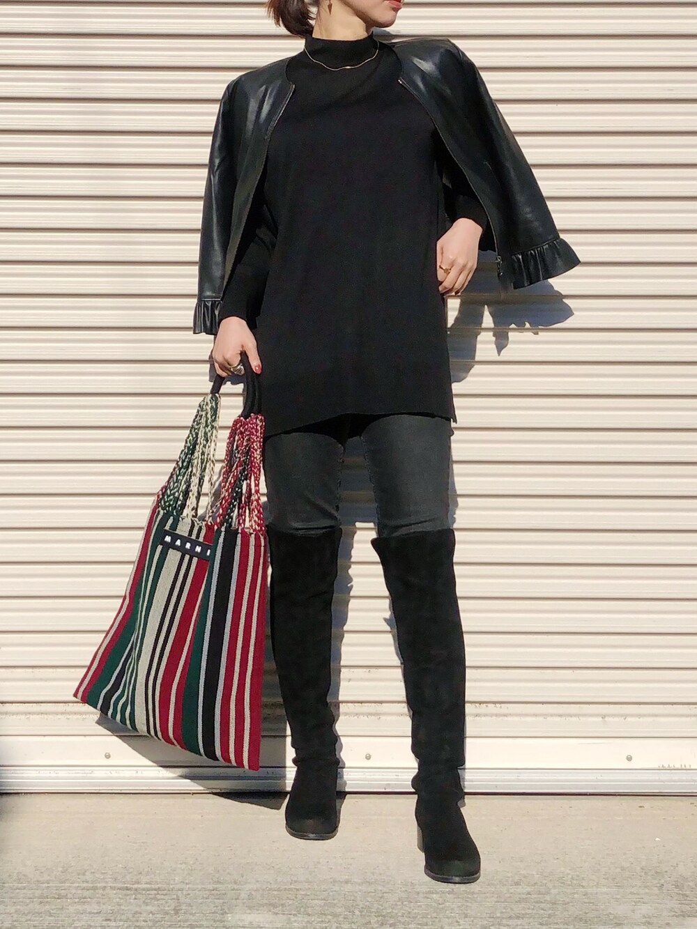 ブラック系のニット/セーター、ブラック系のデニムパンツ、ブラック系のブーツを着用したレディースの秋コーディネートの2枚目の写真