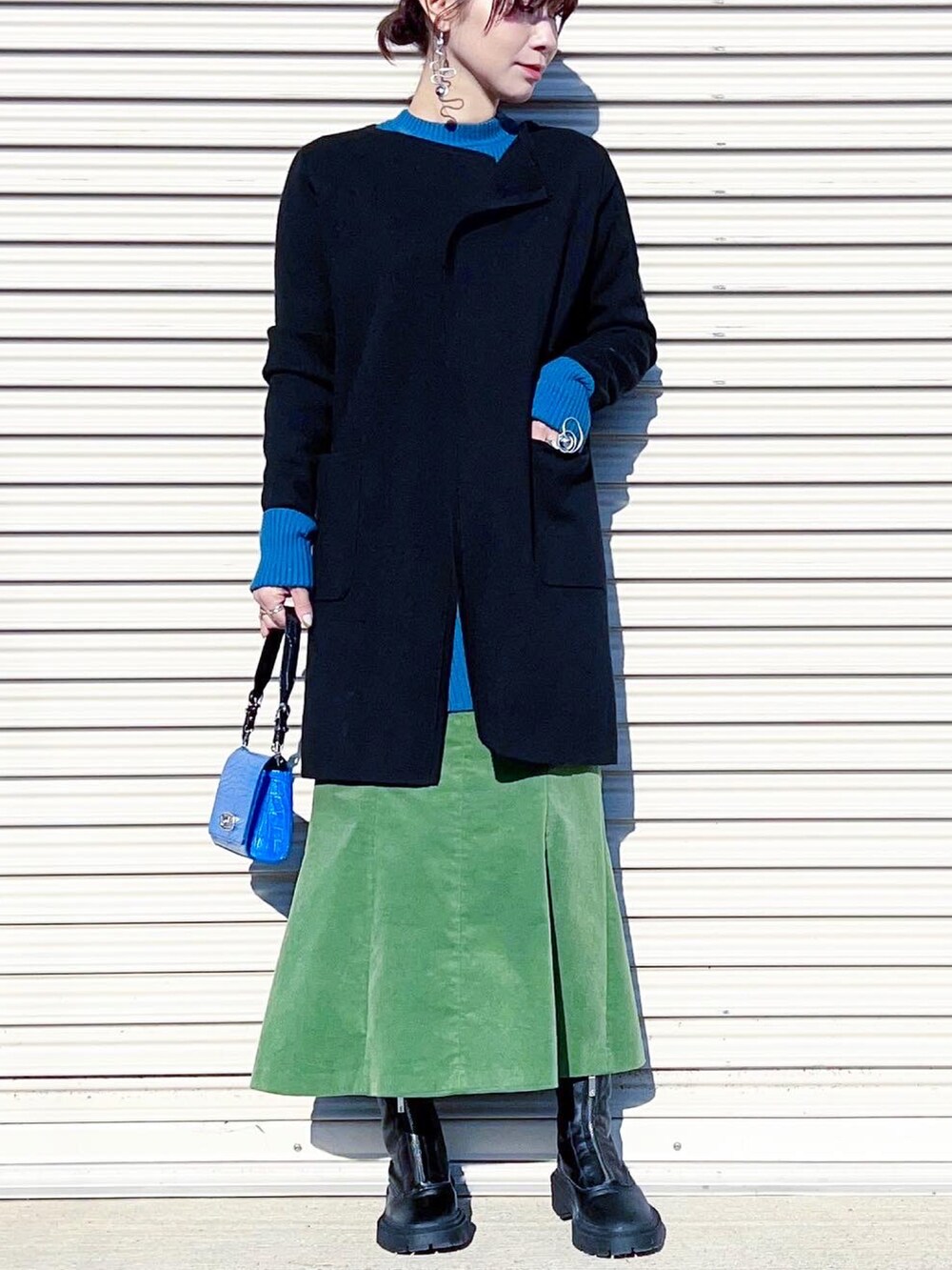 ブルー系のニット/セーター、ブラック系のカーディガン/ボレロ、グリーン系のスカートを着用したレディースの冬コーディネートの3枚目の写真