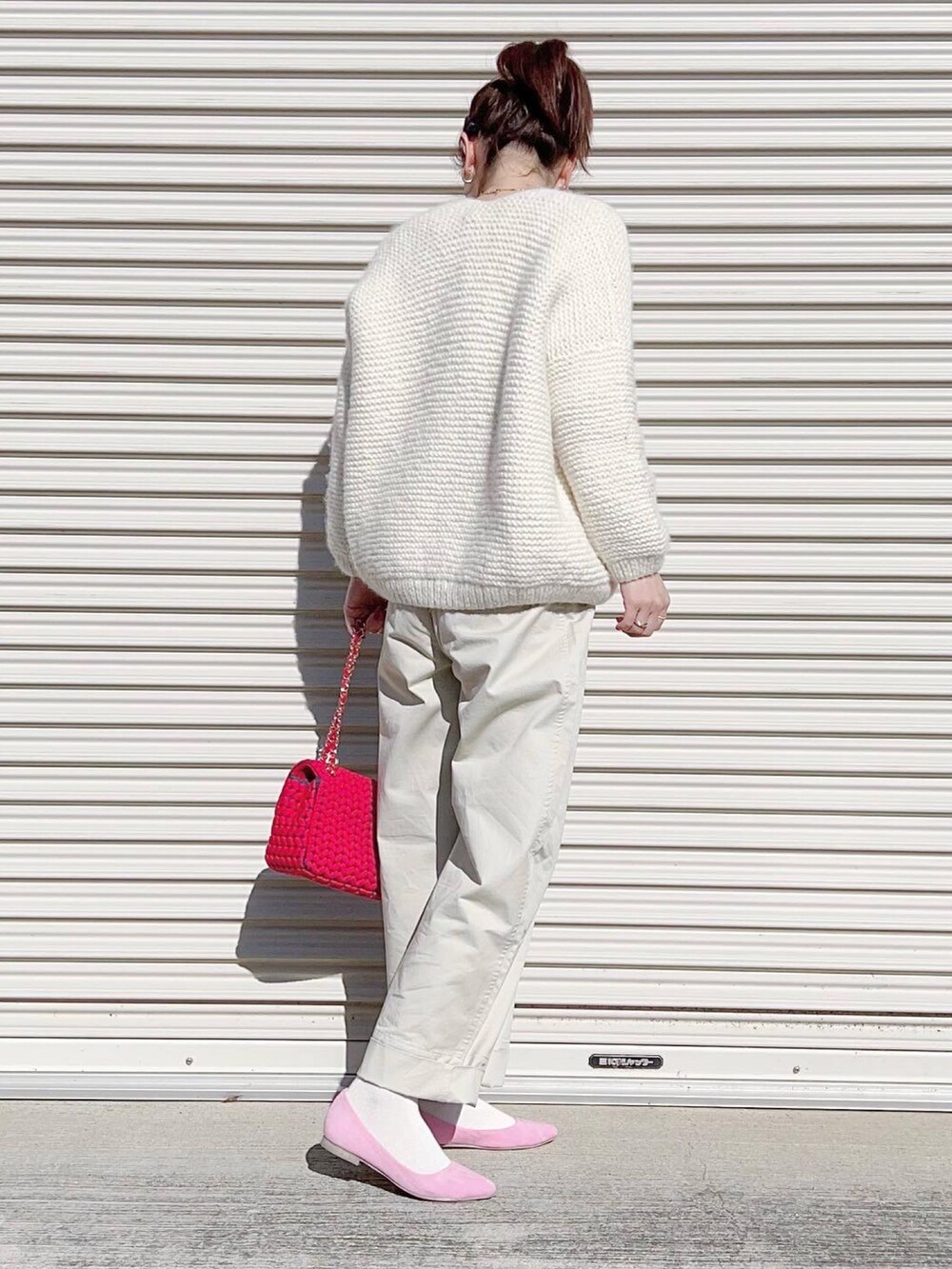 ホワイト系のパンツ、ピンク系のパンプス、レッド系のショルダーバッグを着用したレディースの冬コーディネートの2枚目の写真