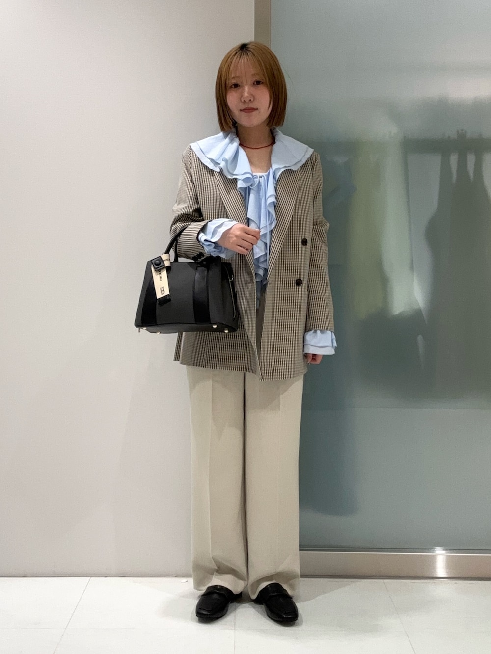 ブラック系のハンドバッグ、ベージュ系のその他パンツ、ブラック系のローファーを着用したレディースの春コーディネートの2枚目の写真