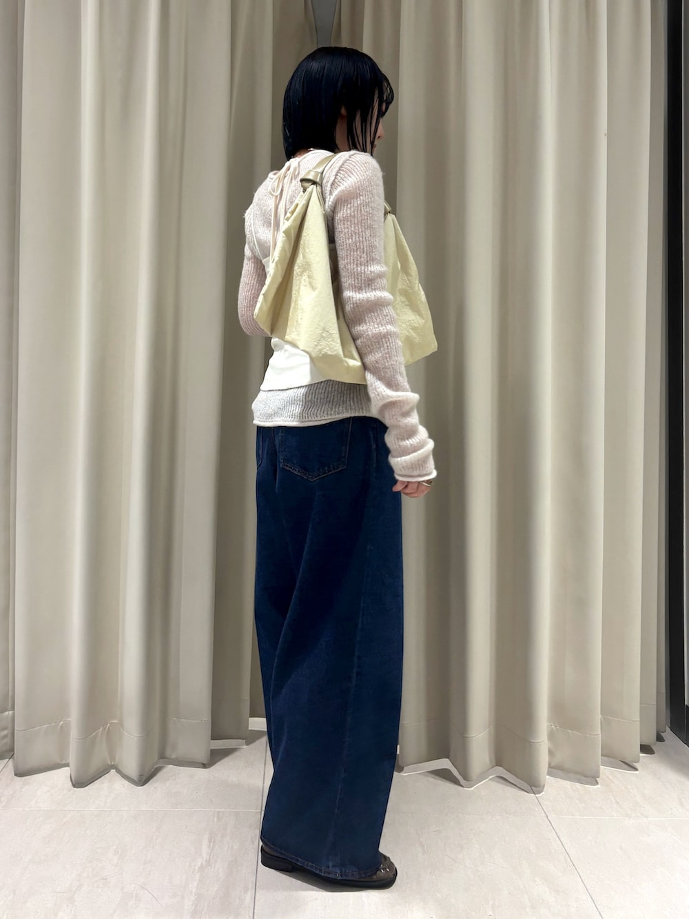 ホワイト系のニット/セーター、ブルー系のデニムパンツ、イエロー系のハンドバッグを着用したレディースの秋コーディネートの4枚目の写真
