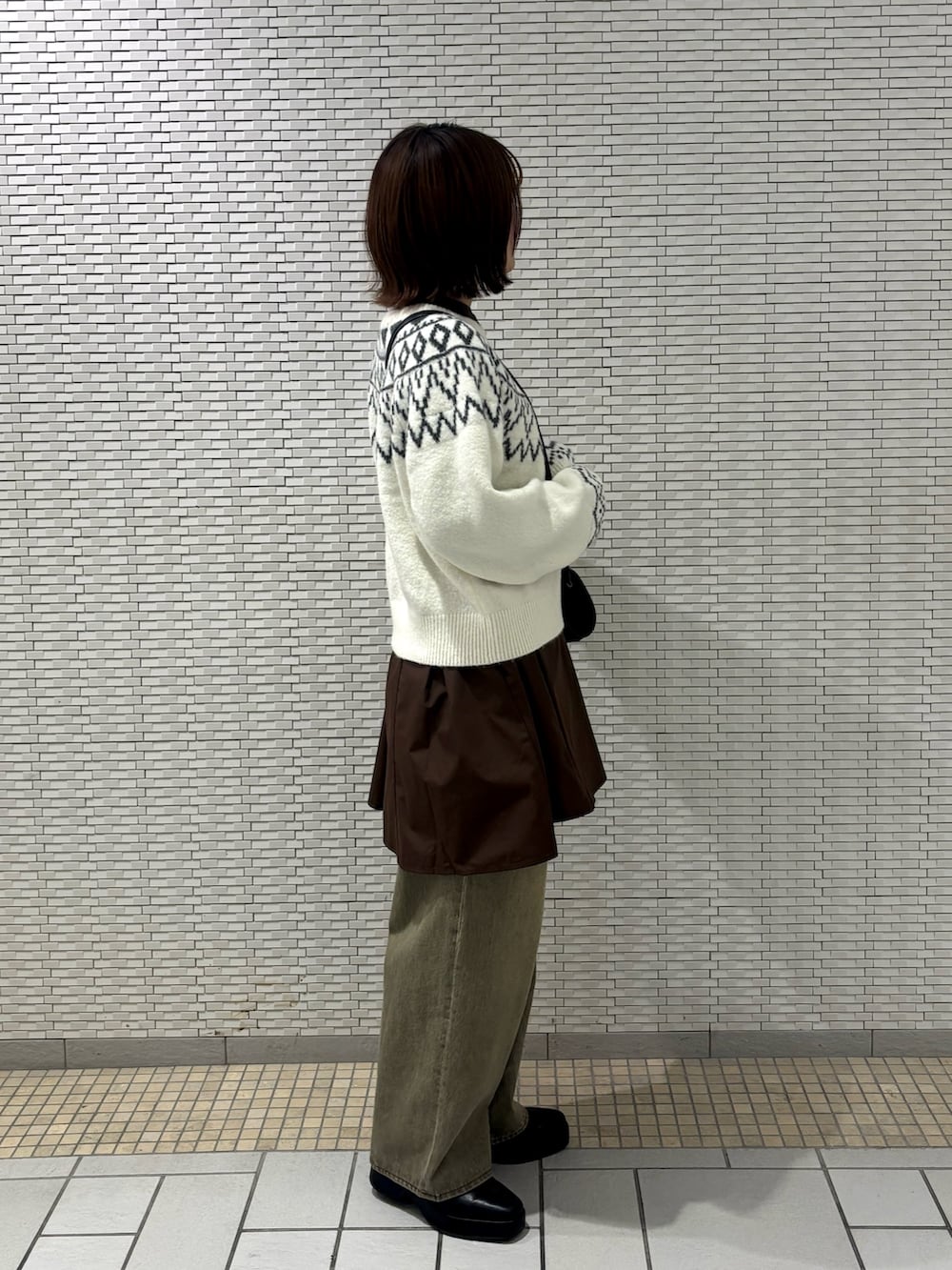 ホワイト系のニット/セーター、グリーン系のデニムパンツ、ブラウン系のワンピースを着用したレディースの冬コーディネートの4枚目の写真