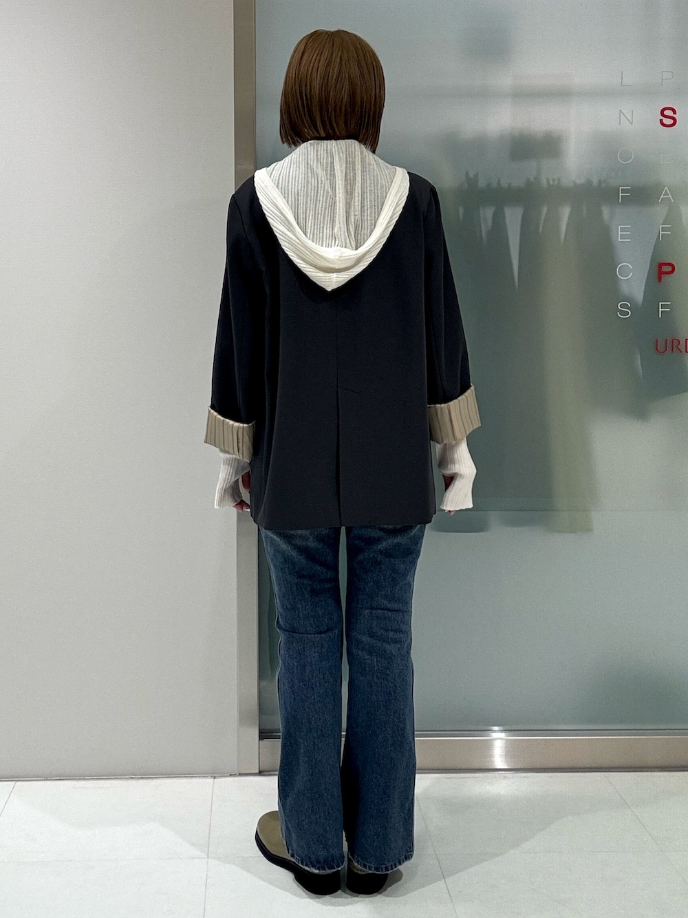 グレー系のテーラードジャケット、ホワイト系のニット/セーター、ブルー系のデニムパンツを着用したレディースの春コーディネートの2枚目の写真