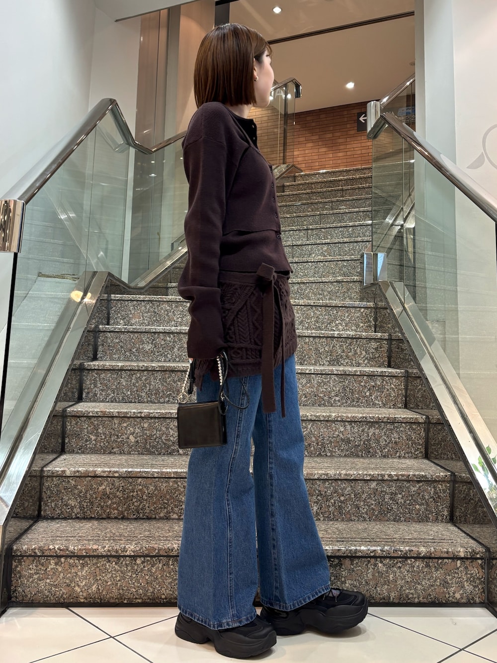 ブラウン系のニット/セーター、ブラウン系のスカート、ブルー系のデニムパンツを着用したレディースの冬コーディネートの4枚目の写真