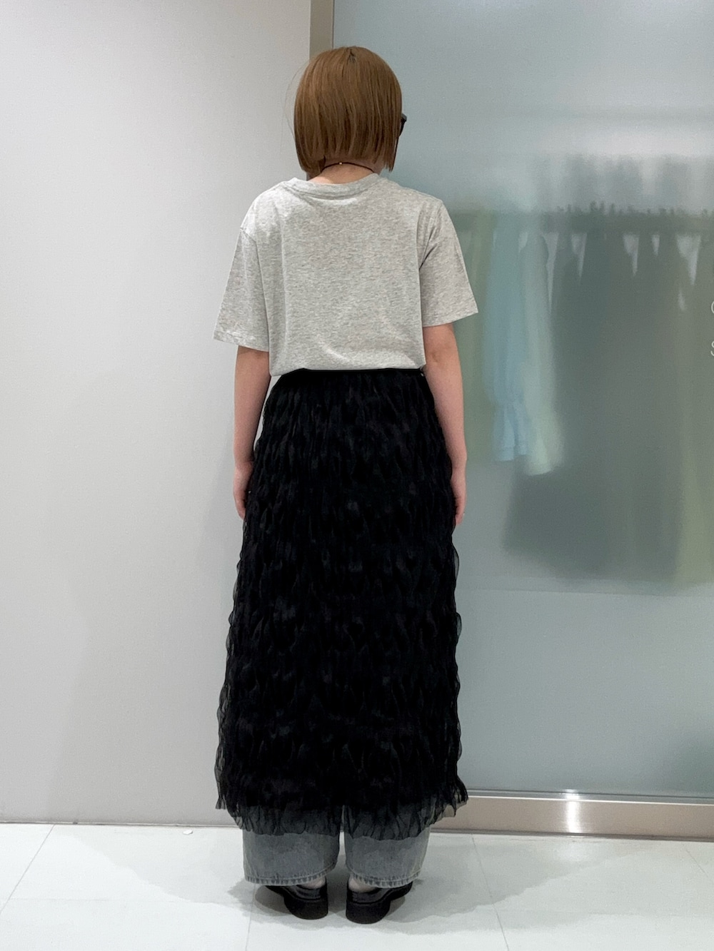 ブルー系のデニムパンツ、ブラック系のスカート、ブラック系のサンダルを着用したレディースの春コーディネートの3枚目の写真