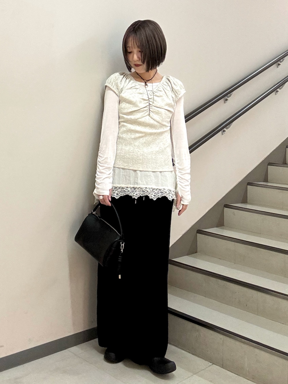 ブラック系のハンドバッグ、ブラック系のスカート、ベージュ系のTシャツ/カットソーを着用したレディースの春コーディネートの6枚目の写真