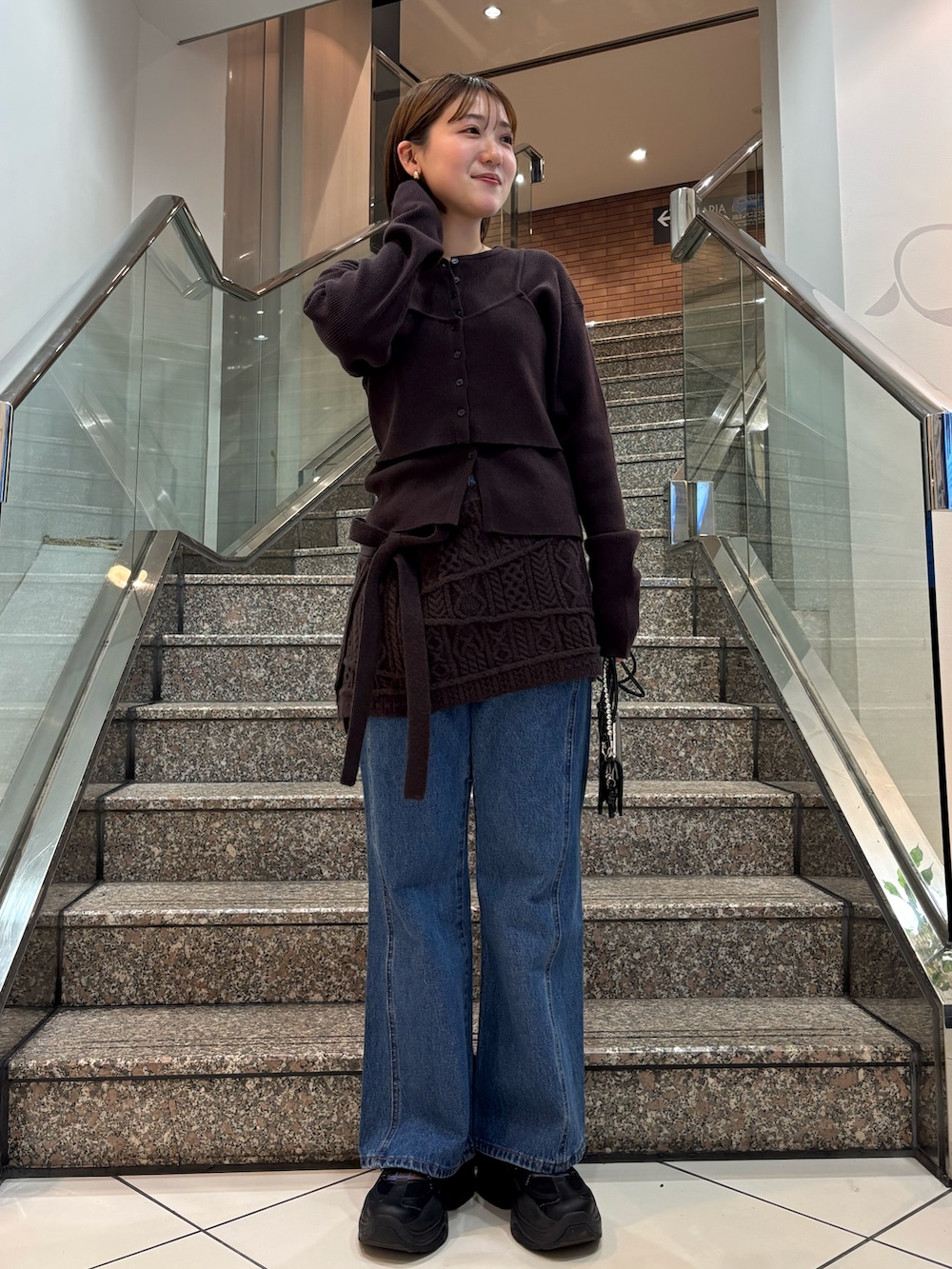 ブラウン系のニット/セーター、ブラウン系のスカート、ブルー系のデニムパンツを着用したレディースの冬コーディネートの3枚目の写真