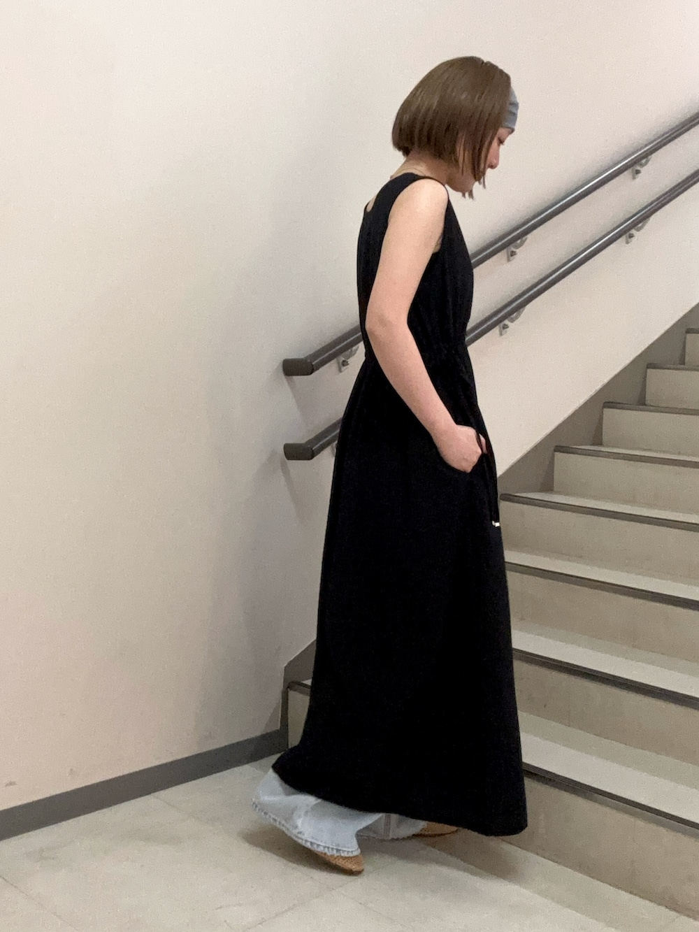 ブラック系のワンピース、ブルー系のデニムパンツ、ベージュ系のショルダーバッグを着用したレディースの夏コーディネートの5枚目の写真