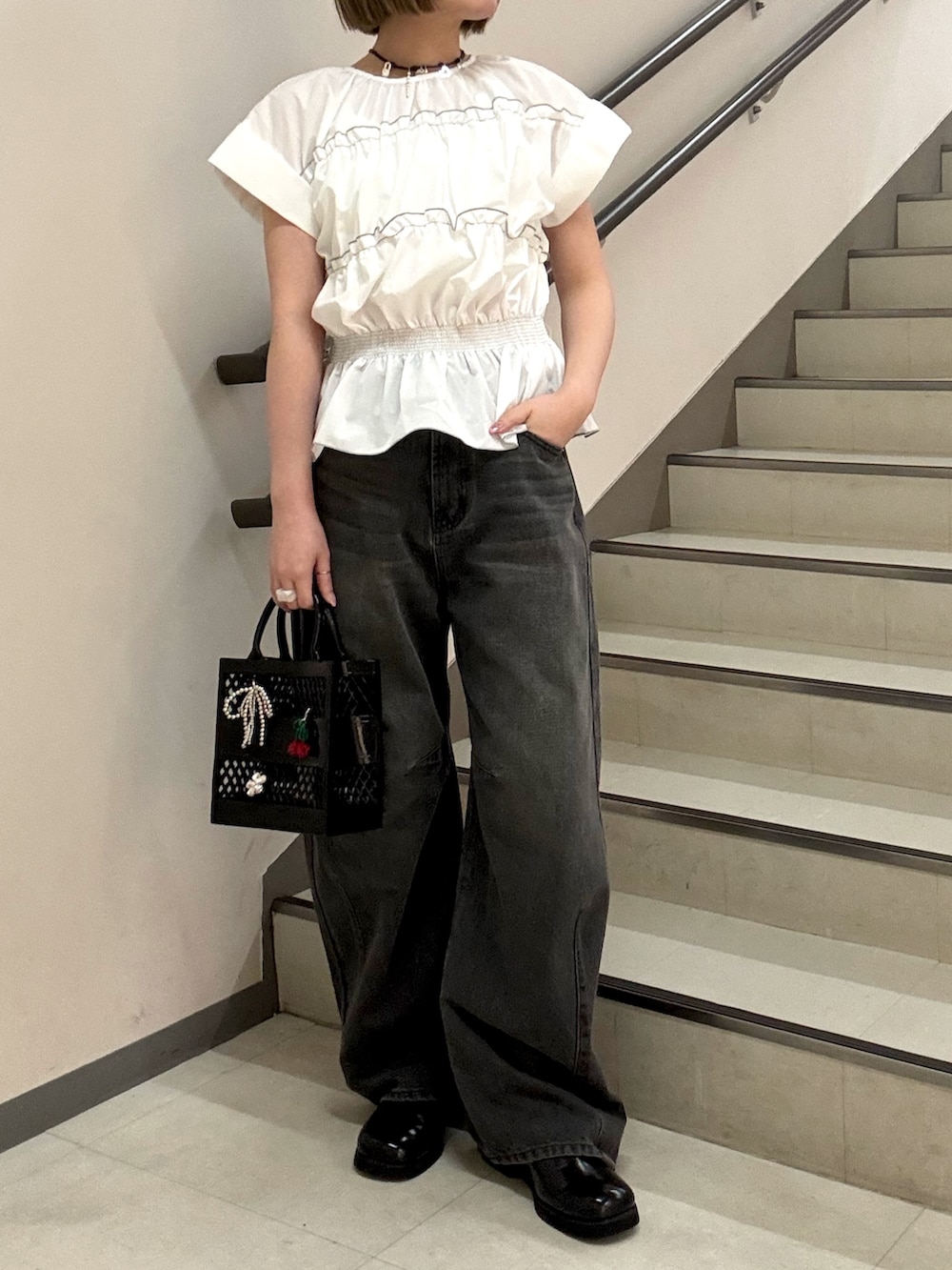 グレー系のデニムパンツ、ホワイト系のシャツ/ブラウス、ブラック系のハンドバッグを着用したレディースの春コーディネートの2枚目の写真