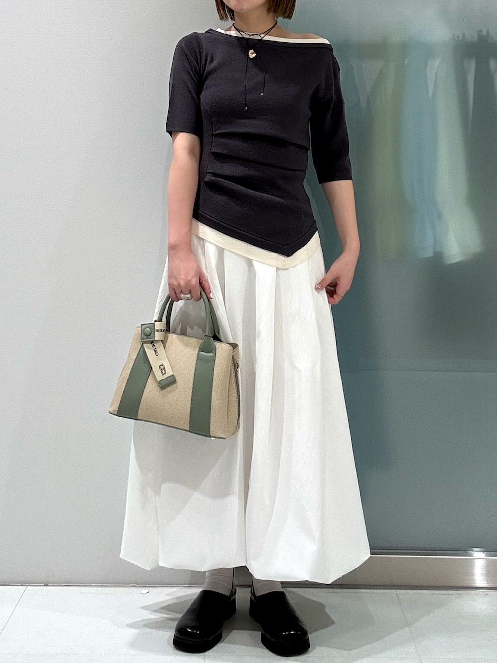 ホワイト系のスカート、ホワイト系のハンドバッグ、ブラック系のサンダルを着用したレディースの春コーディネートの3枚目の写真
