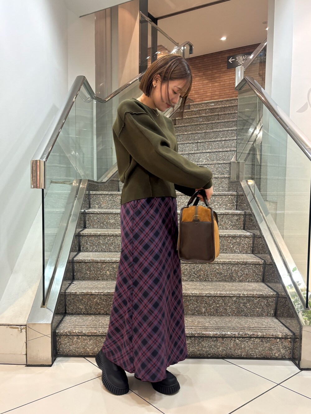 ブラック系のスニーカー、レッド系のスカート、イエロー系のボストンバッグを着用したレディースの冬コーディネートの3枚目の写真