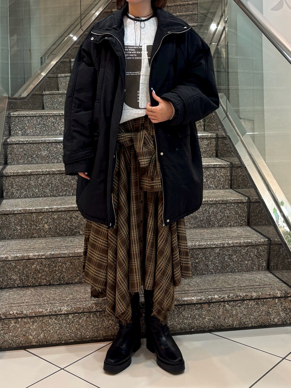 グレー系のTシャツ/カットソー、ブラウン系のスカート、ブラック系のダウンジャケット/コートを着用したレディースの冬コーディネートの4枚目の写真