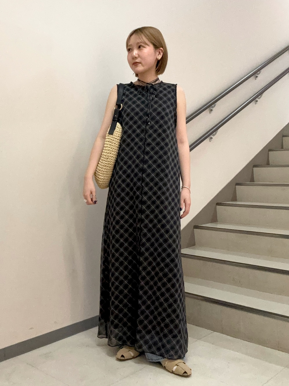 ブラック系のワンピース、ベージュ系のサンダル、ブルー系のデニムパンツを着用したレディースの春コーディネートの5枚目の写真