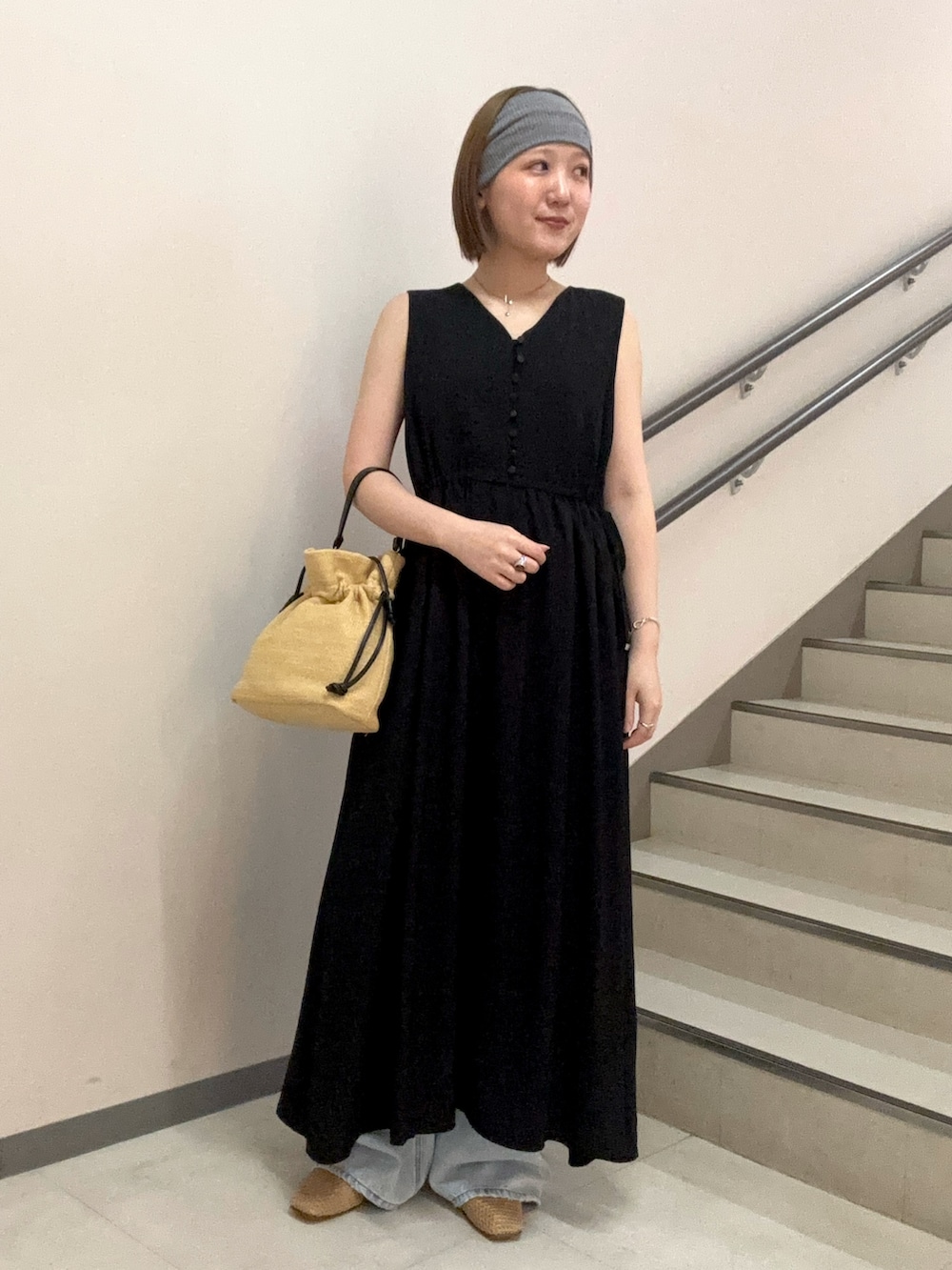 ブラック系のワンピース、ブルー系のデニムパンツ、ベージュ系のショルダーバッグを着用したレディースの夏コーディネートの3枚目の写真