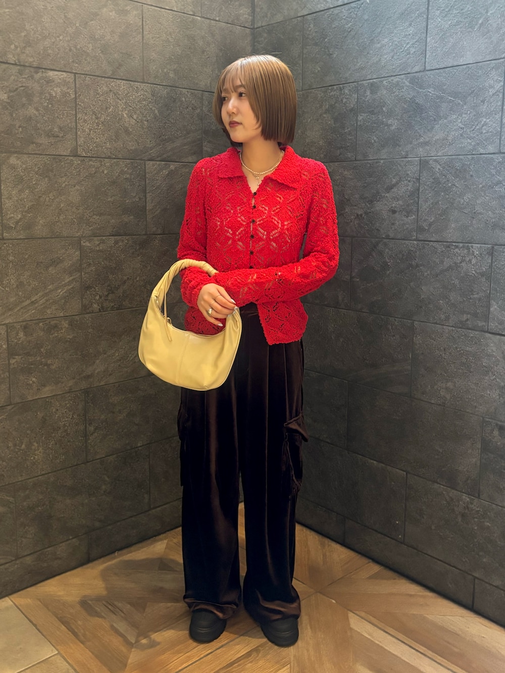 レッド系のニット/セーター、ブラウン系のその他パンツ、ホワイト系のハンドバッグを着用したレディースの冬コーディネートの3枚目の写真