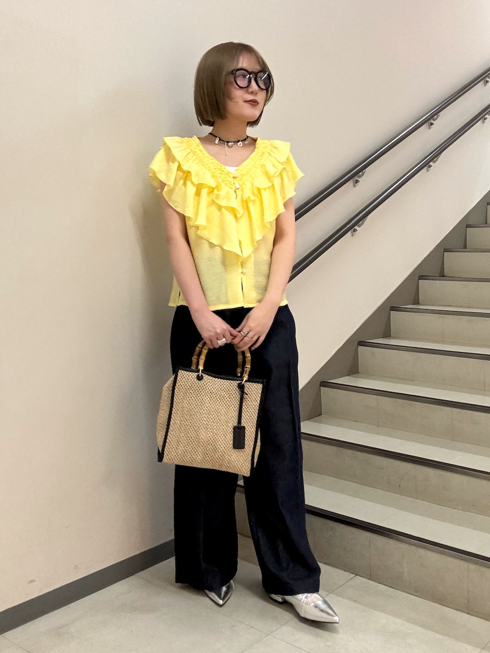 イエロー系のシャツ/ブラウス、シルバー系のパンプス、ブラック系のショルダーバッグを着用したレディースの春コーディネートの2枚目の写真