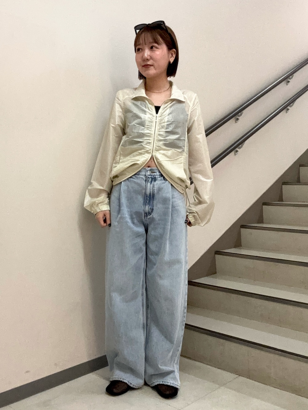 ブルー系のデニムパンツ、ブラック系のキャミソール、ホワイト系のブルゾンを着用したレディースの春コーディネートの2枚目の写真