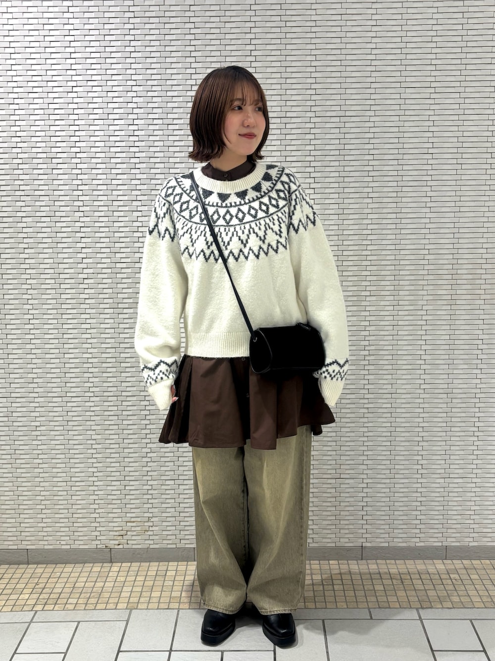 ホワイト系のニット/セーター、グリーン系のデニムパンツ、ブラウン系のワンピースを着用したレディースの冬コーディネートの2枚目の写真