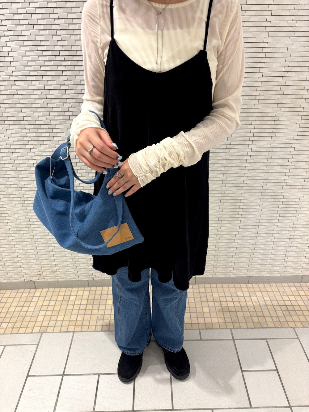 ホワイト系のTシャツ/カットソー、ブラック系のワンピース、ブルー系のデニムパンツを着用したレディースの秋コーディネートの3枚目の写真