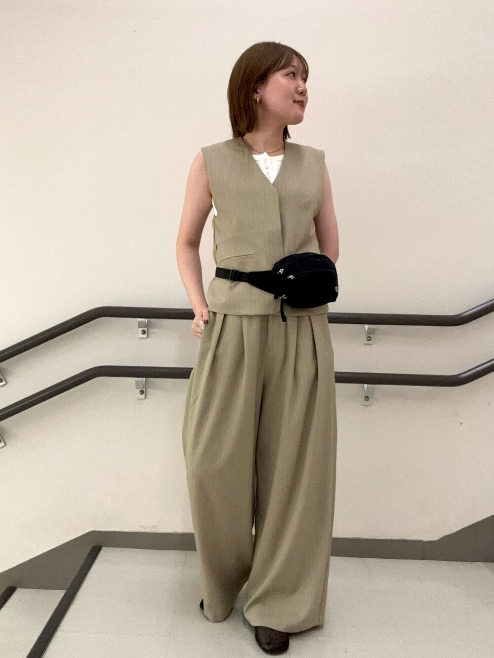 ベージュ系のスラックス、ベージュ系のベスト、ホワイト系のタンクトップを着用したレディースの夏コーディネートの5枚目の写真