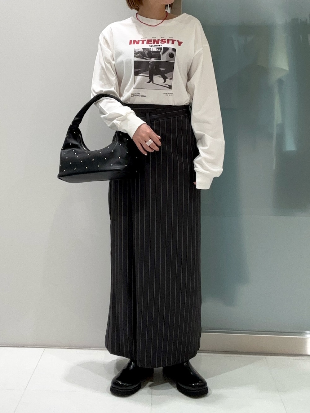 グレー系のスカート、その他のTシャツ/カットソー、ブラック系のハンドバッグを着用したレディースの春コーディネートの2枚目の写真