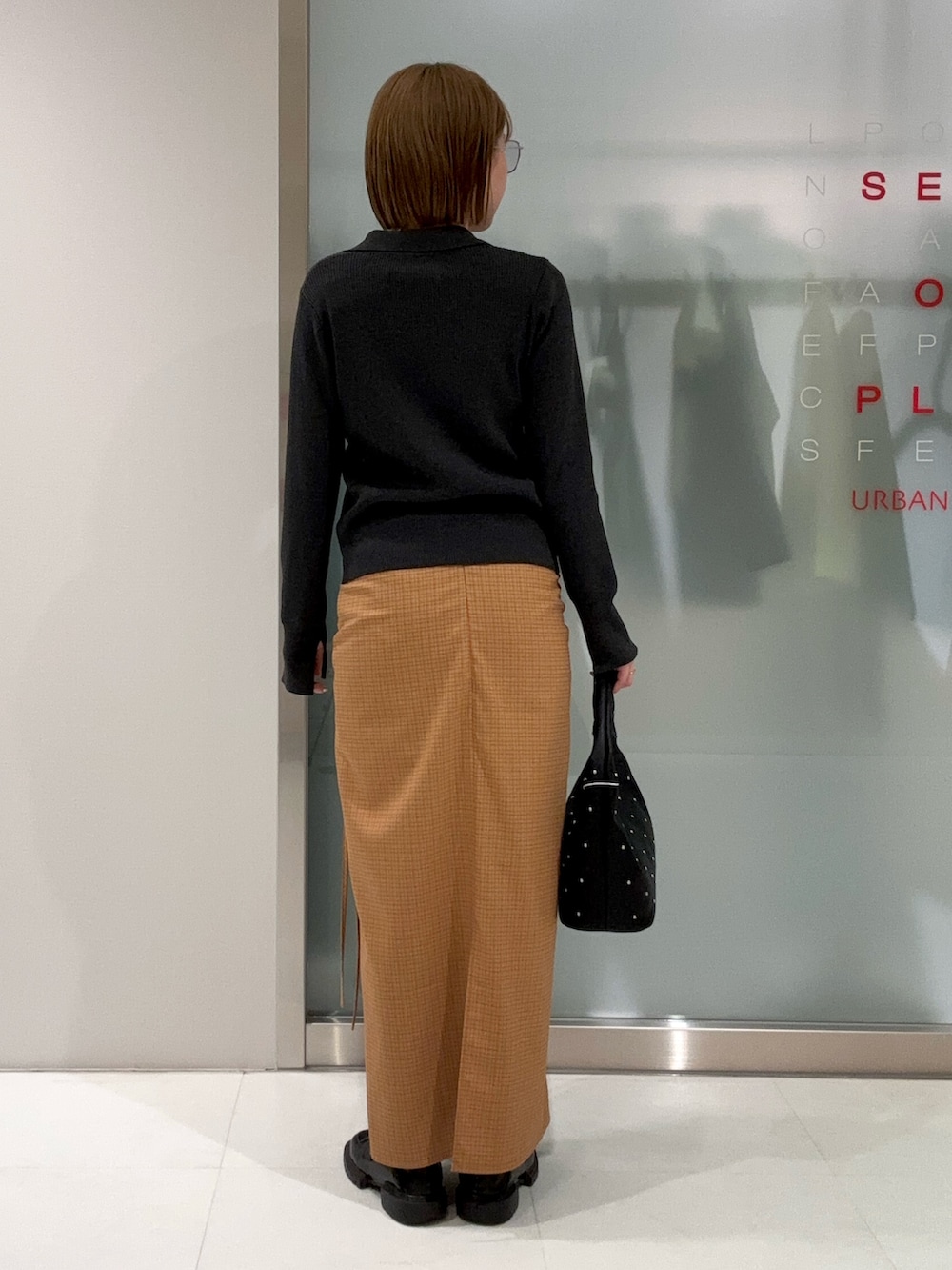 グレー系のカーディガン/ボレロ、ブラック系のハンドバッグ、イエロー系のスカートを着用したレディースの春コーディネートの4枚目の写真