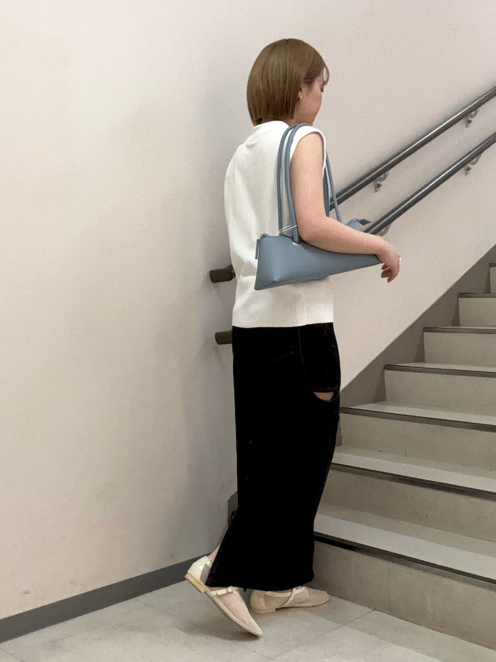ホワイト系のベスト、ブルー系のショルダーバッグ、ホワイト系のパンプスを着用したレディースの春コーディネートの2枚目の写真