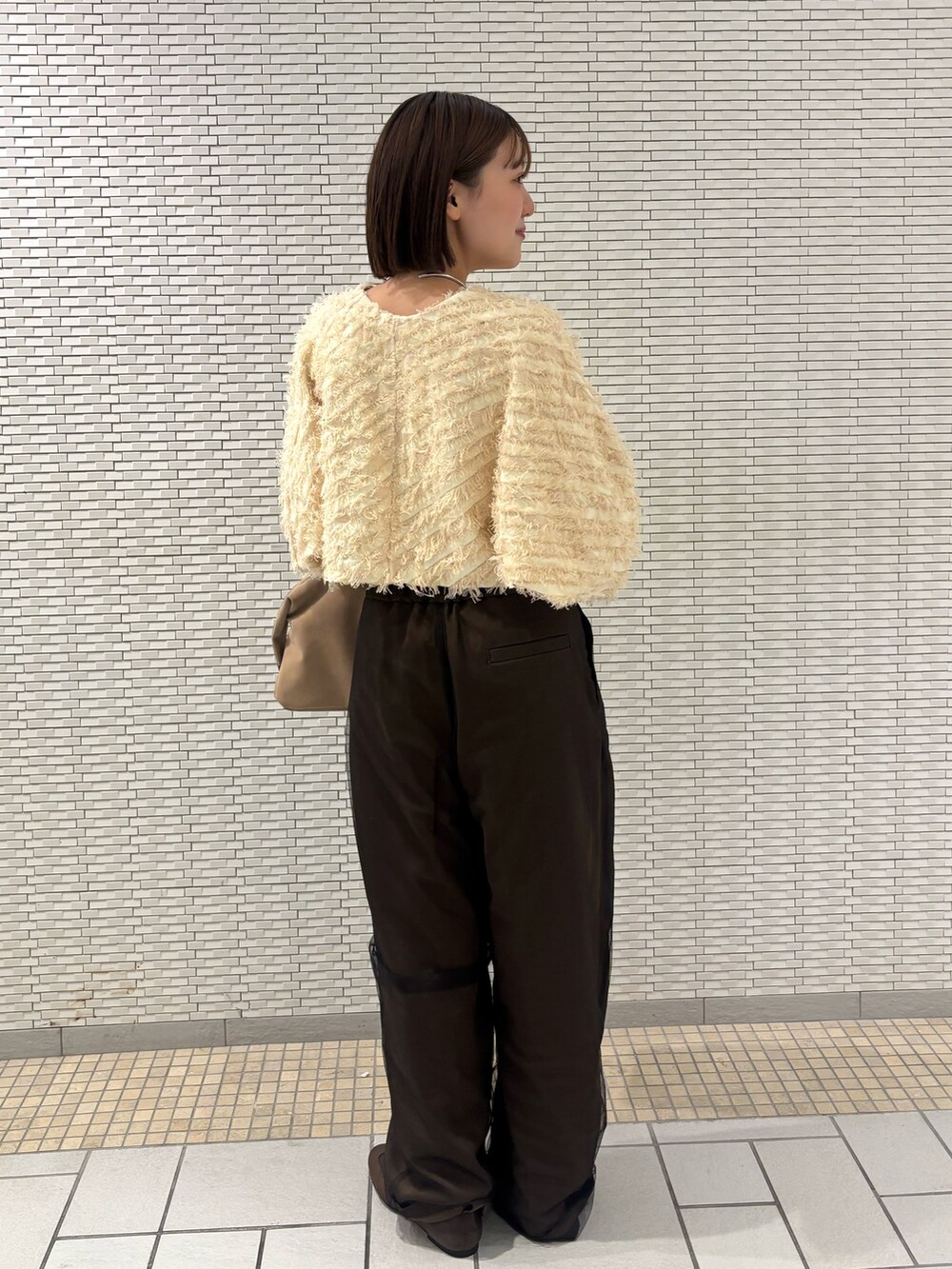 ベージュ系のボストンバッグ、ブラウン系のその他パンツ、ブラウン系のスニーカーを着用したレディースの冬コーディネートの3枚目の写真