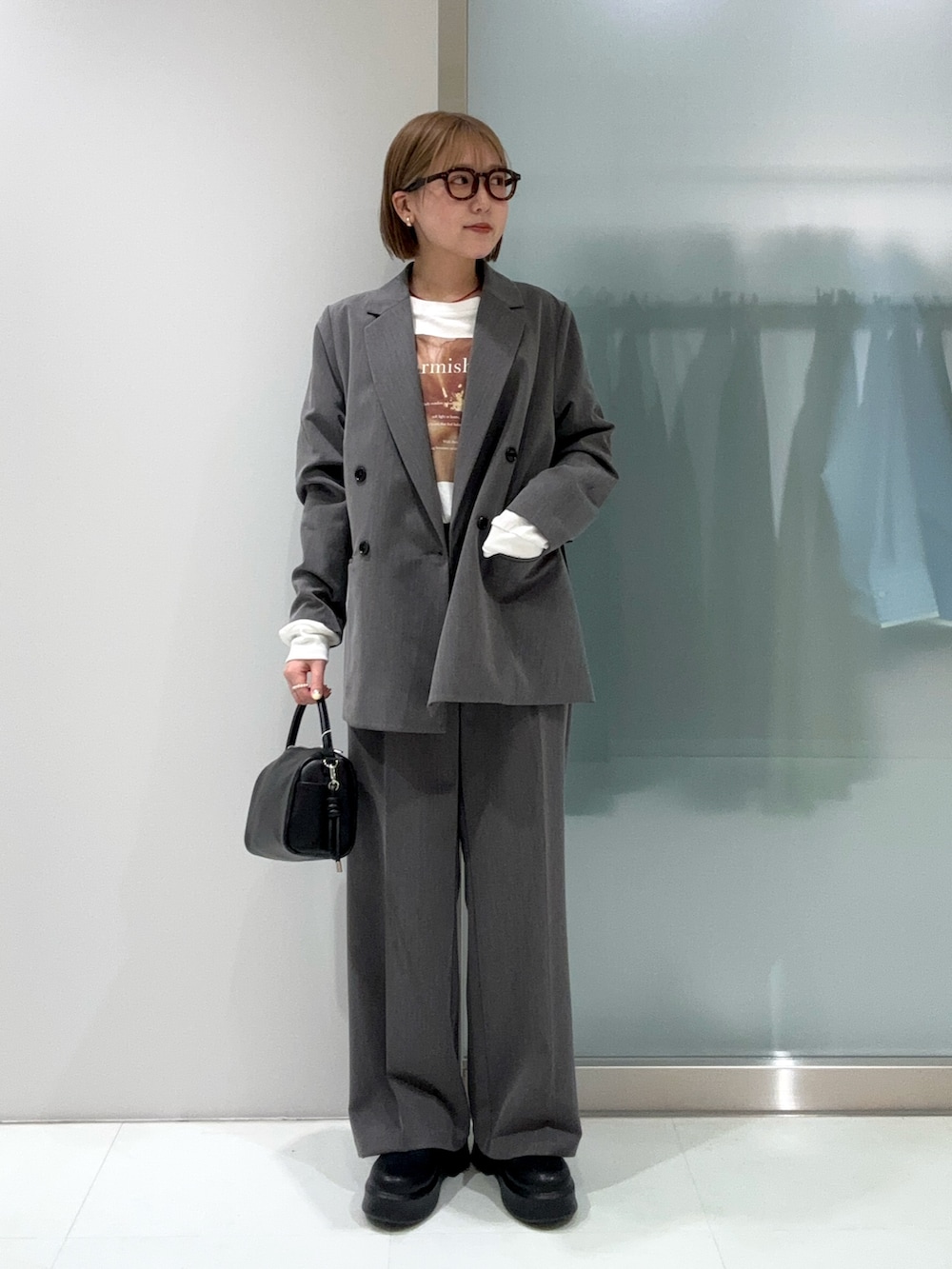 グレー系のスラックス、ブラック系のハンドバッグ、ブラック系のその他シューズを着用したレディースの春コーディネートの2枚目の写真