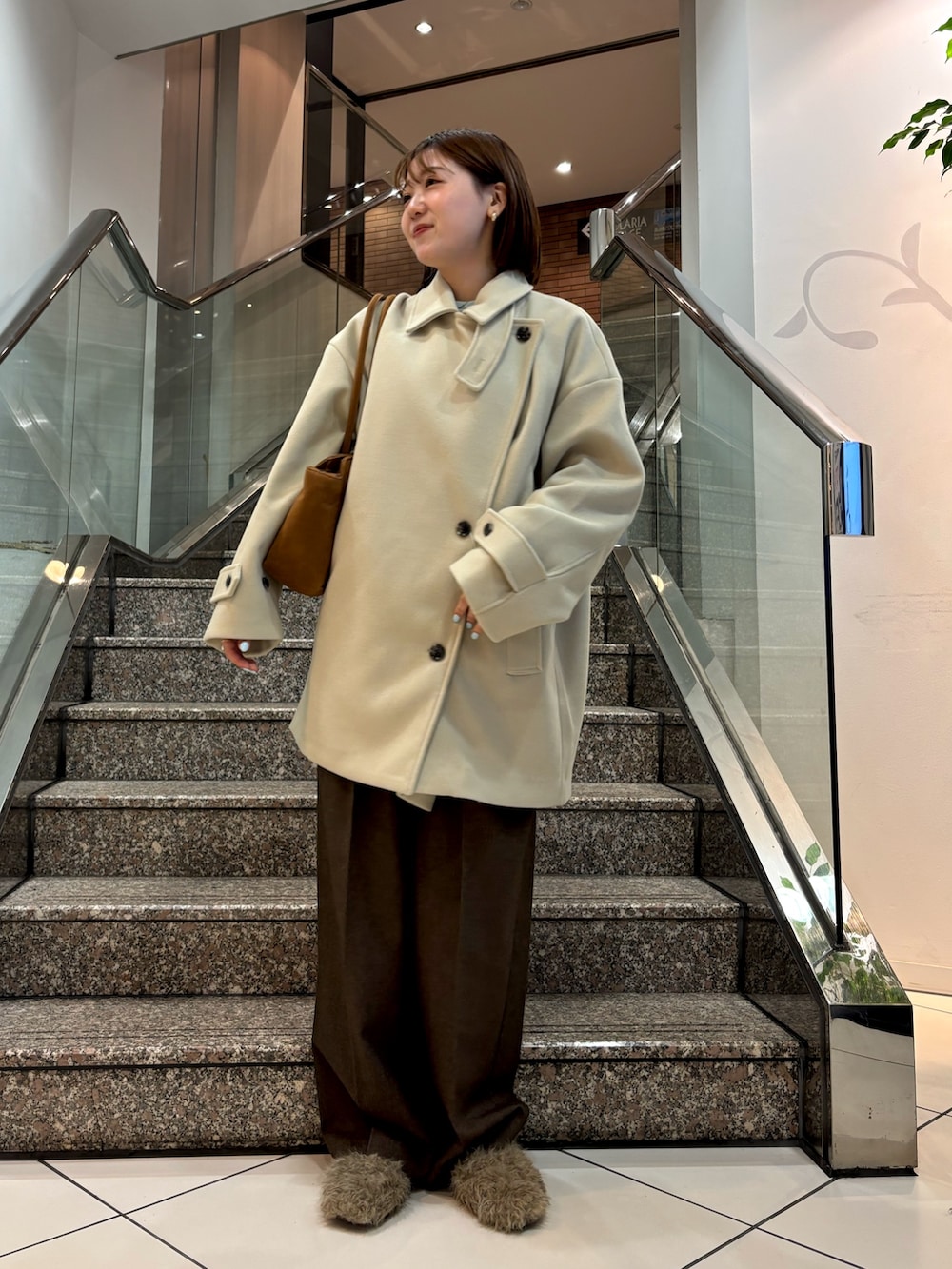 ブルー系のTシャツ/カットソー、イエロー系のボストンバッグ、ベージュ系のその他アウターを着用したレディースの冬コーディネートの4枚目の写真