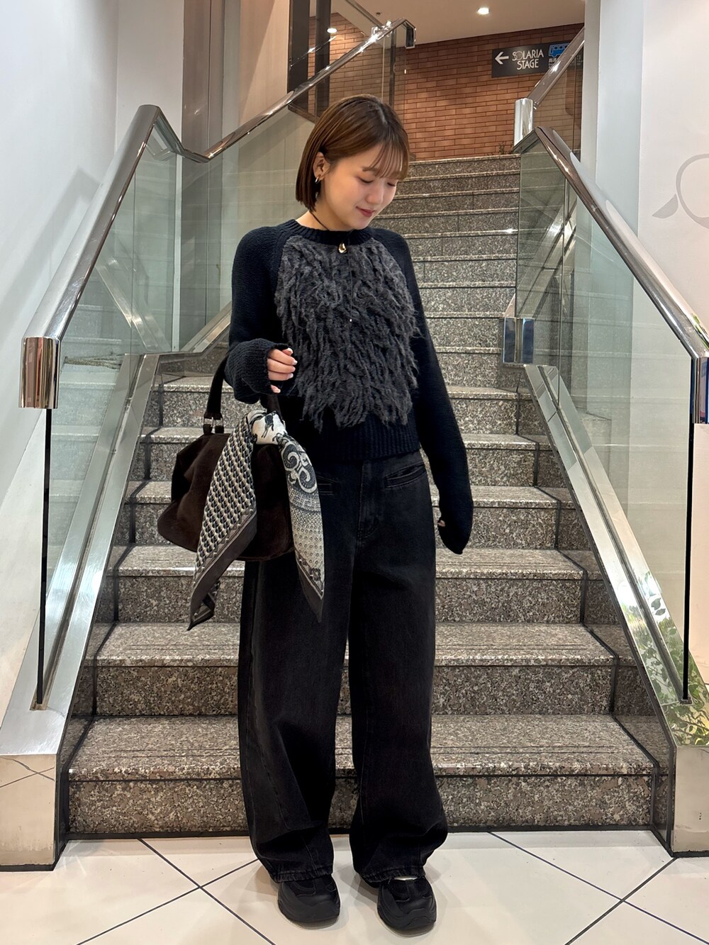 グレー系のニット/セーター、ブラック系のデニムパンツ、ブラウン系のボストンバッグを着用したレディースの冬コーディネートの4枚目の写真