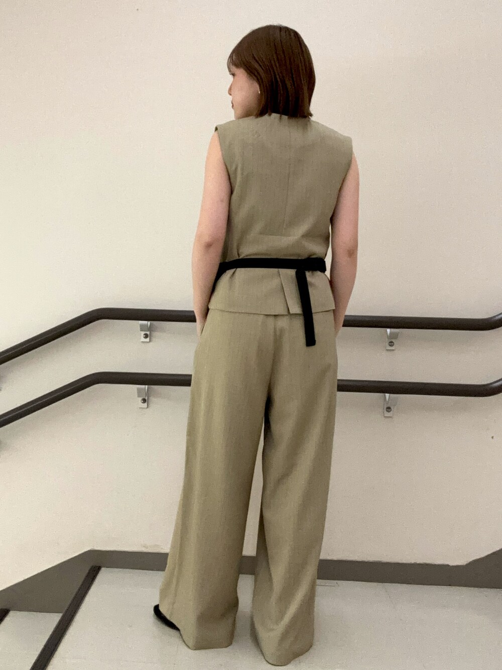 ベージュ系のスラックス、ベージュ系のベスト、ホワイト系のタンクトップを着用したレディースの夏コーディネートの4枚目の写真