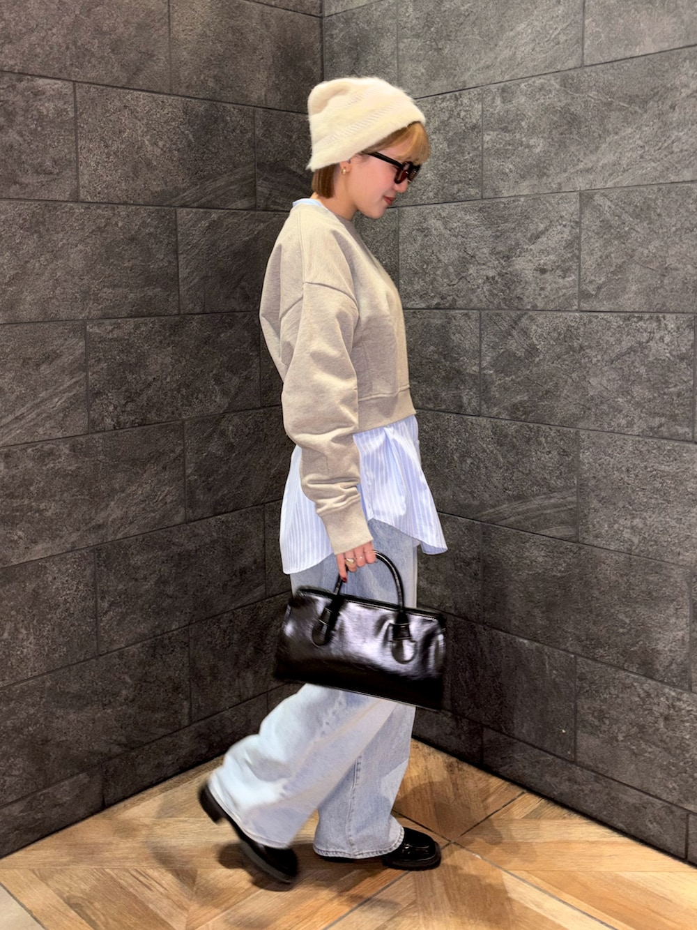 ブラック系のボストンバッグ、ブルー系のデニムパンツ、ベージュ系のスウェットを着用したレディースの冬コーディネートの4枚目の写真