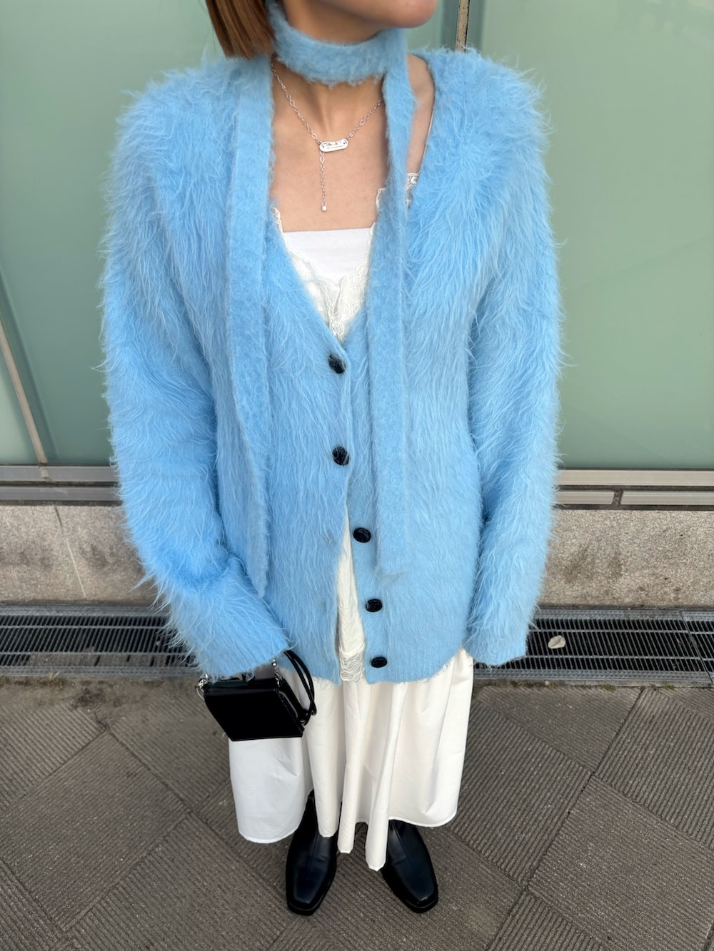 ブルー系のカーディガン/ボレロ、ホワイト系のキャミソール、ホワイト系のスカートを着用したレディースの冬コーディネートの4枚目の写真