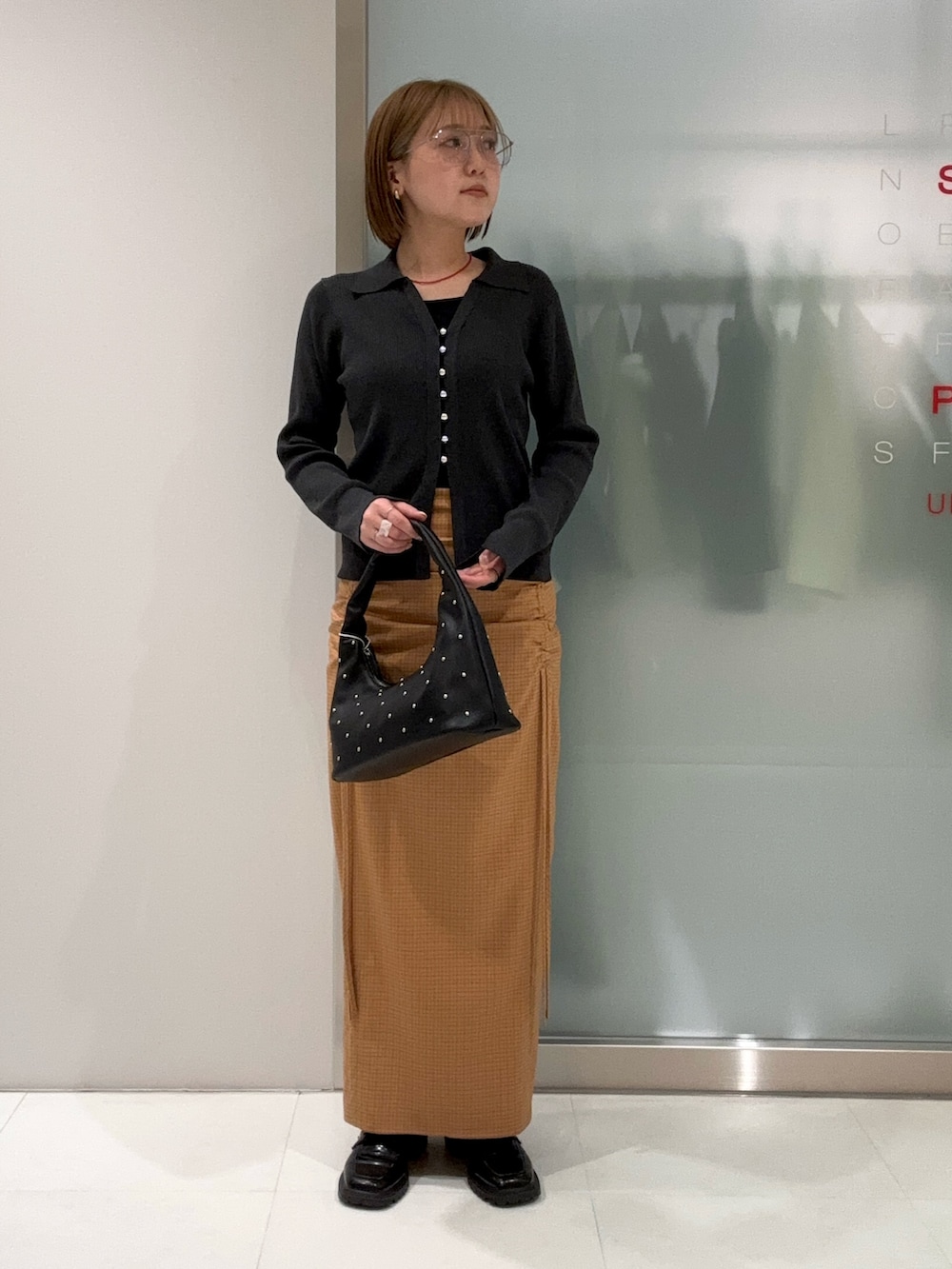 グレー系のカーディガン/ボレロ、ブラック系のハンドバッグ、イエロー系のスカートを着用したレディースの春コーディネートの2枚目の写真