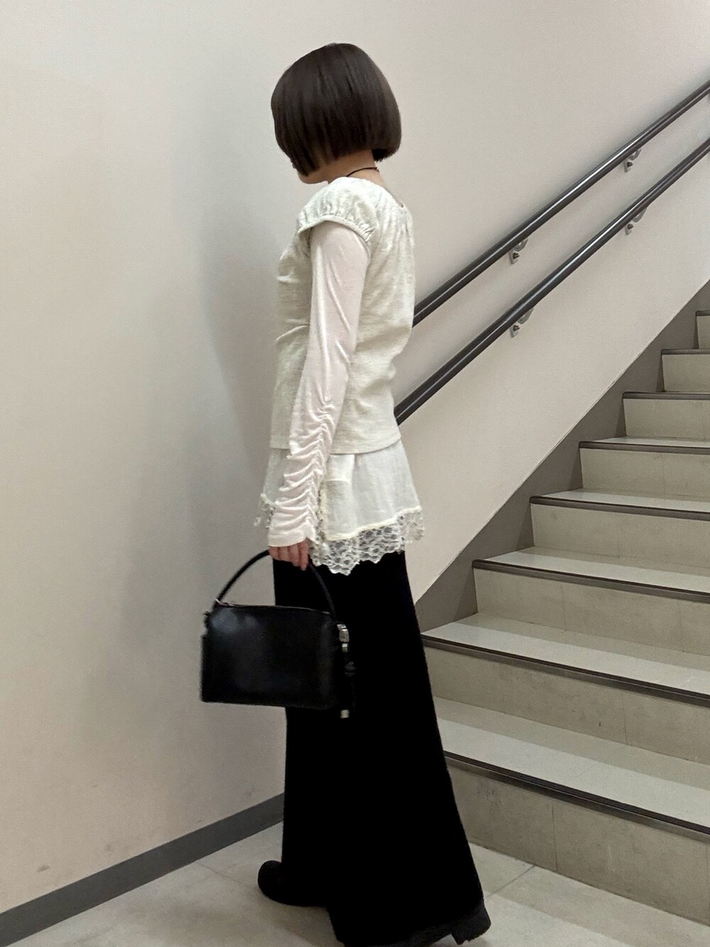 ブラック系のハンドバッグ、ブラック系のスカート、ベージュ系のTシャツ/カットソーを着用したレディースの春コーディネートの5枚目の写真