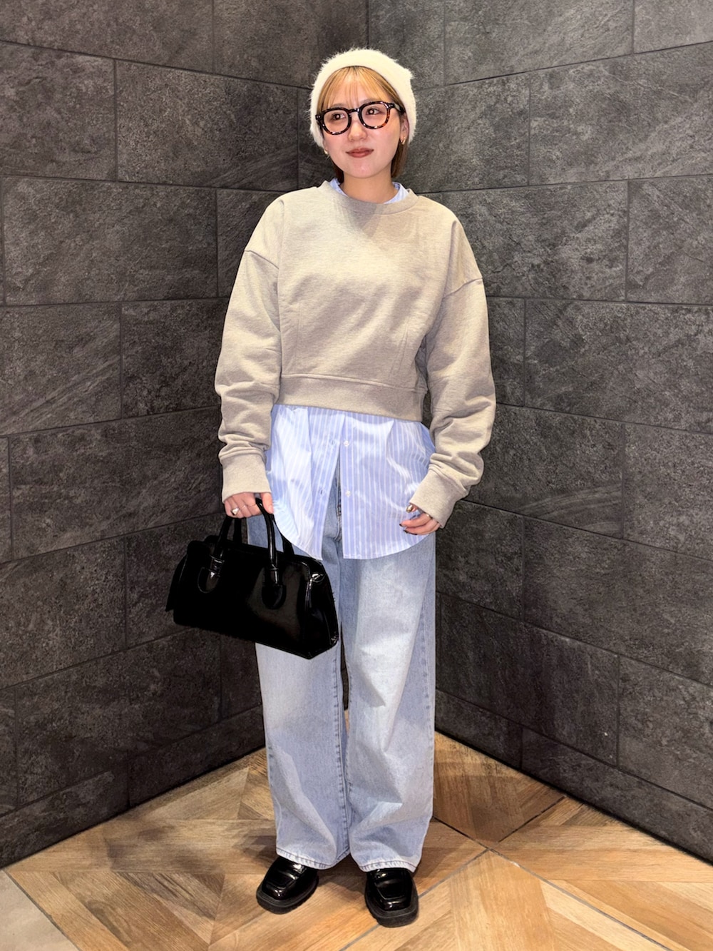 ブラック系のボストンバッグ、ブルー系のデニムパンツ、ベージュ系のスウェットを着用したレディースの冬コーディネートの2枚目の写真