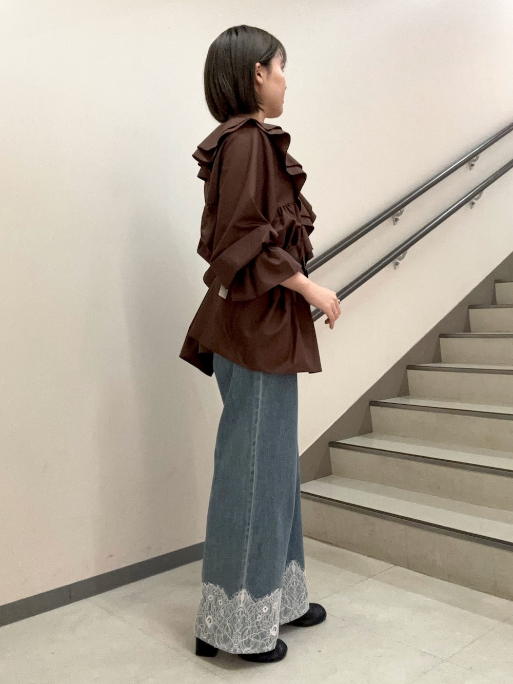 ブラウン系のワンピース、ブルー系のデニムパンツ、ブラック系のスリッポンを着用したレディースの夏コーディネートの2枚目の写真